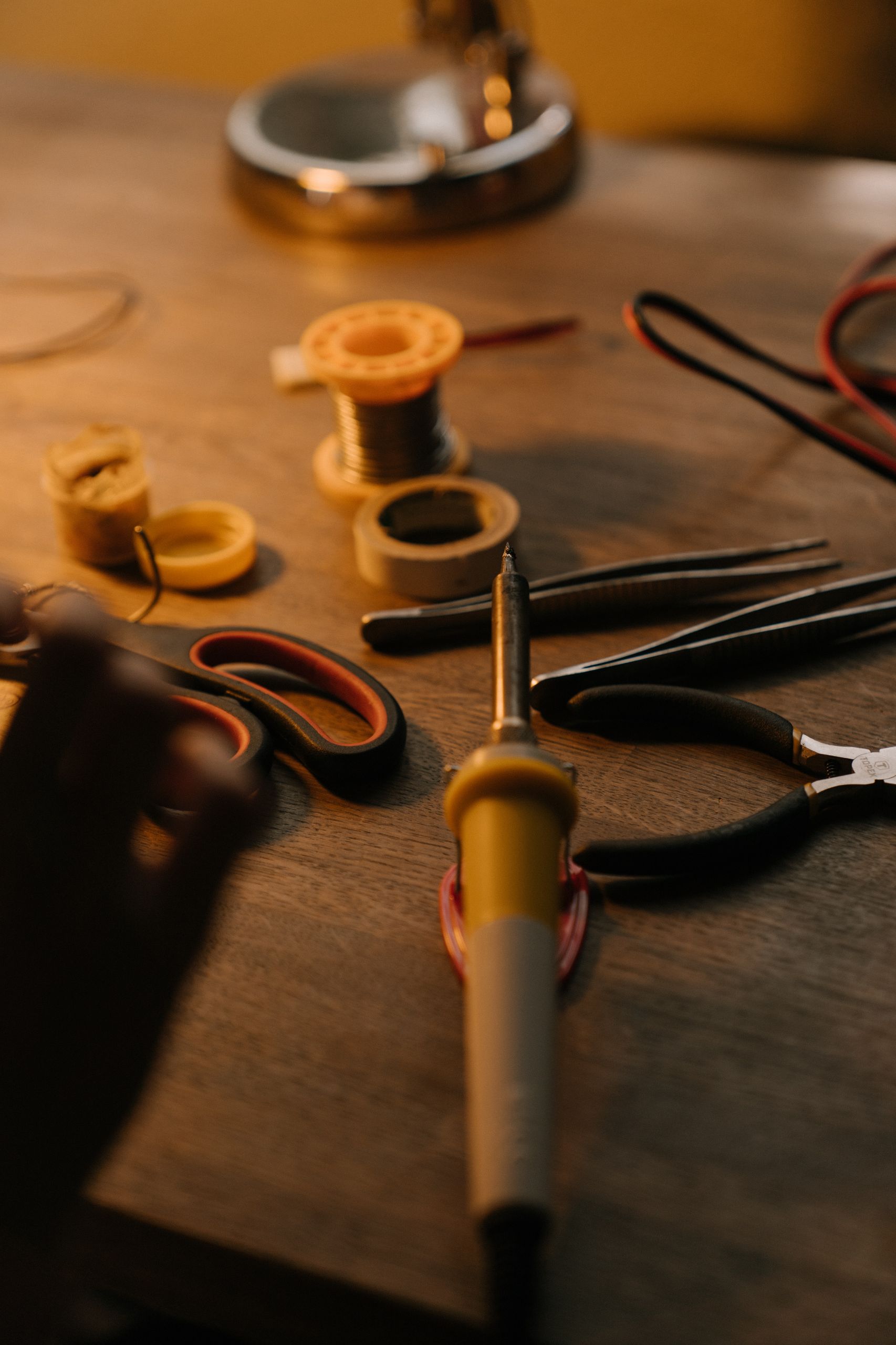 A close-up view of soldering and electronic repair tools on a wooden workbench.